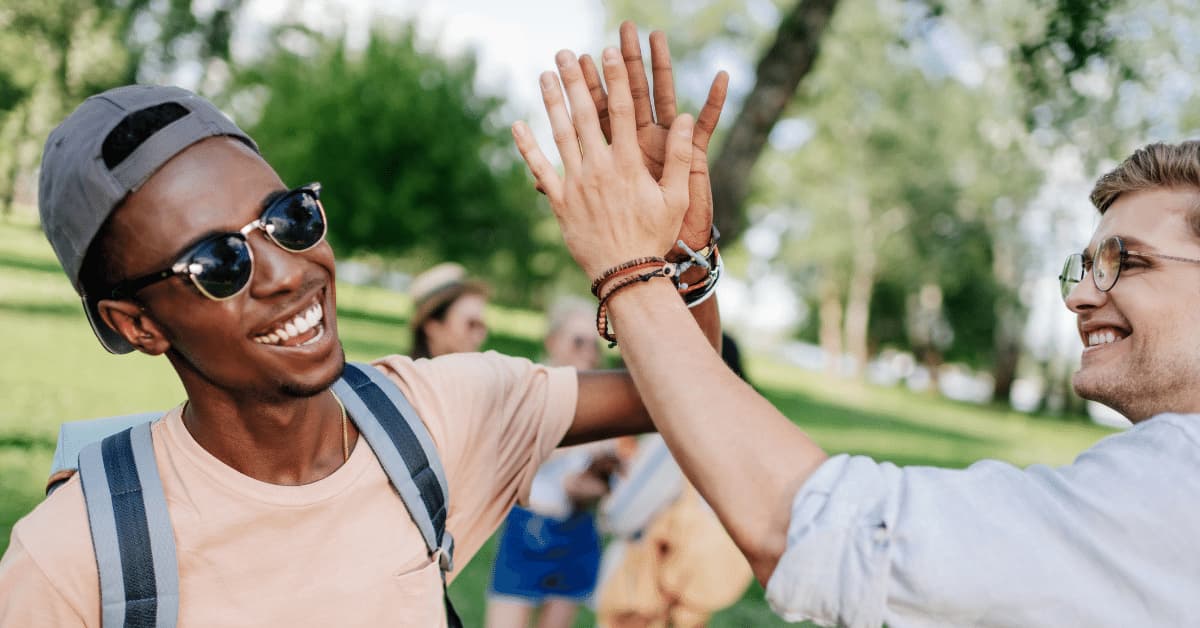 Two young men giving high fives and looking happy.